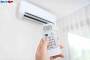 Individual using a remote control to operate a garage AC unit, ensuring efficient garage AC repair and comfort.