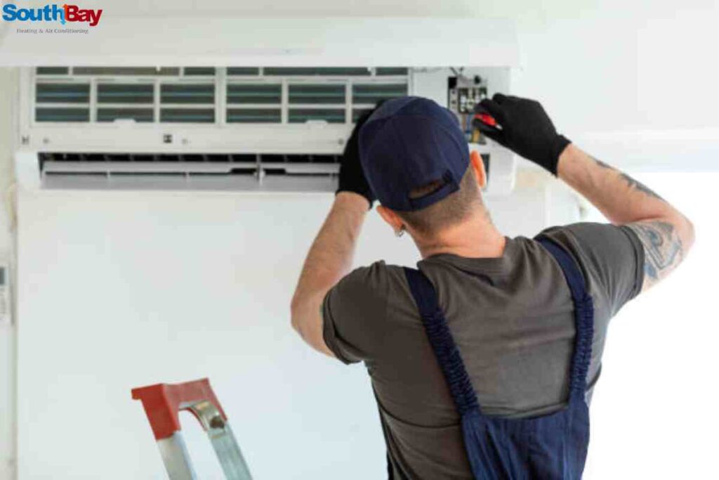 A man performing emergency AC repair, using tools to work on the internal components of an air conditioner.