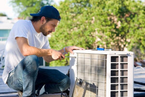 Technician installing a sliding window AC unit in a small room window.
