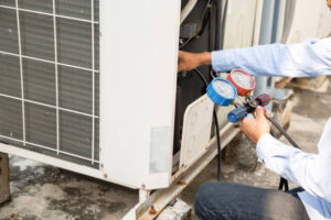 A technician performing sliding window AC installation with tools in hand for a small room unit.