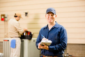  man in a blue shirt holds a clipboard, standing next to an HVAC unit labeled "AC Not Cooling."