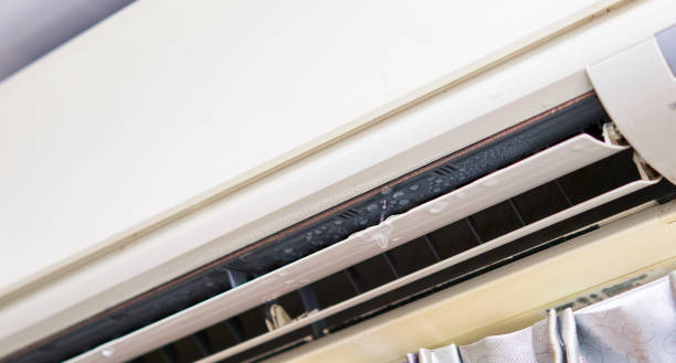 Technician inspecting an air conditioning unit for a water leak , focusing on repair work.