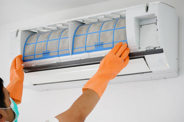 A person uses a power tool to clean a window, focusing on AC coil cleaning for improved efficiency.