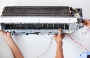A man performs Maintenance of AC Systems on an air conditioning unit, ensuring it operates efficiently and reliably.
